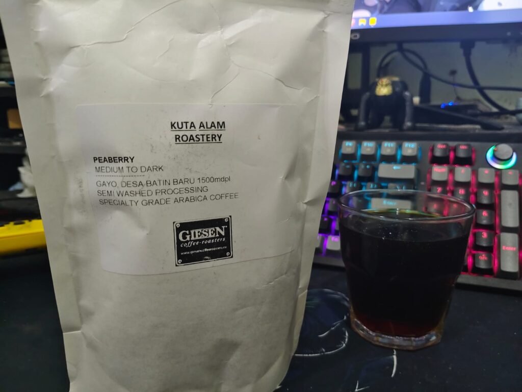 Kopi Kuta alam dengan beans peaberry di atas meja di belakang keyboard
