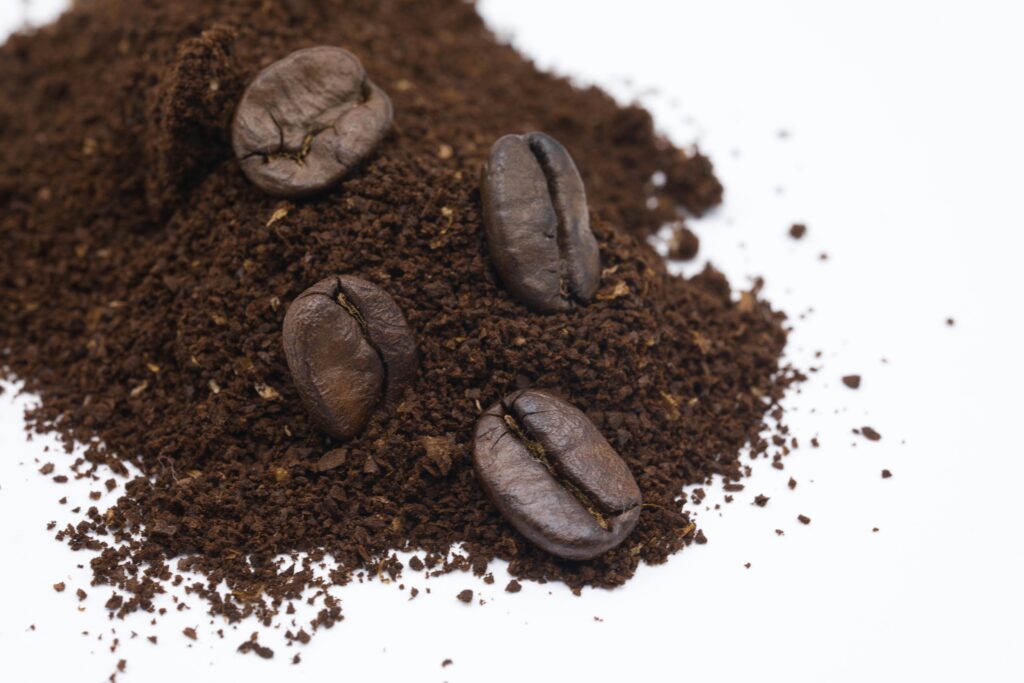 Detailed close-up of roasted coffee beans and ground coffee on a white background.