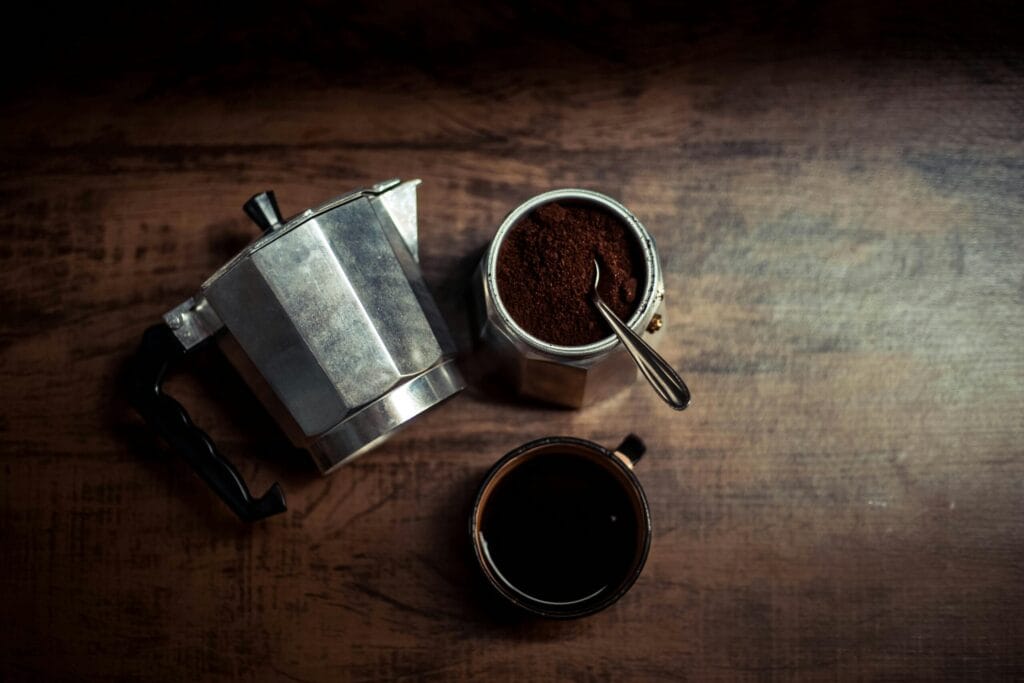 A stylish top-down shot of a moka pot and coffee cup on a wooden surface, perfect for rustic kitchen themes.
